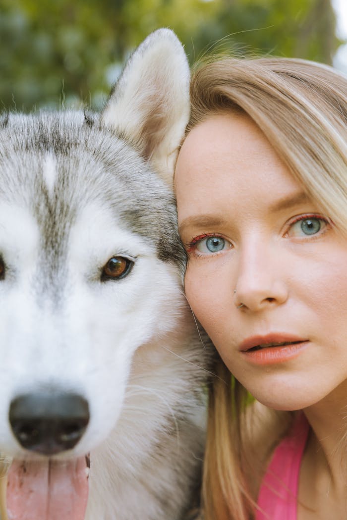 A close-up image of a caucasian woman with a Siberian husky, showing an intimate bond.